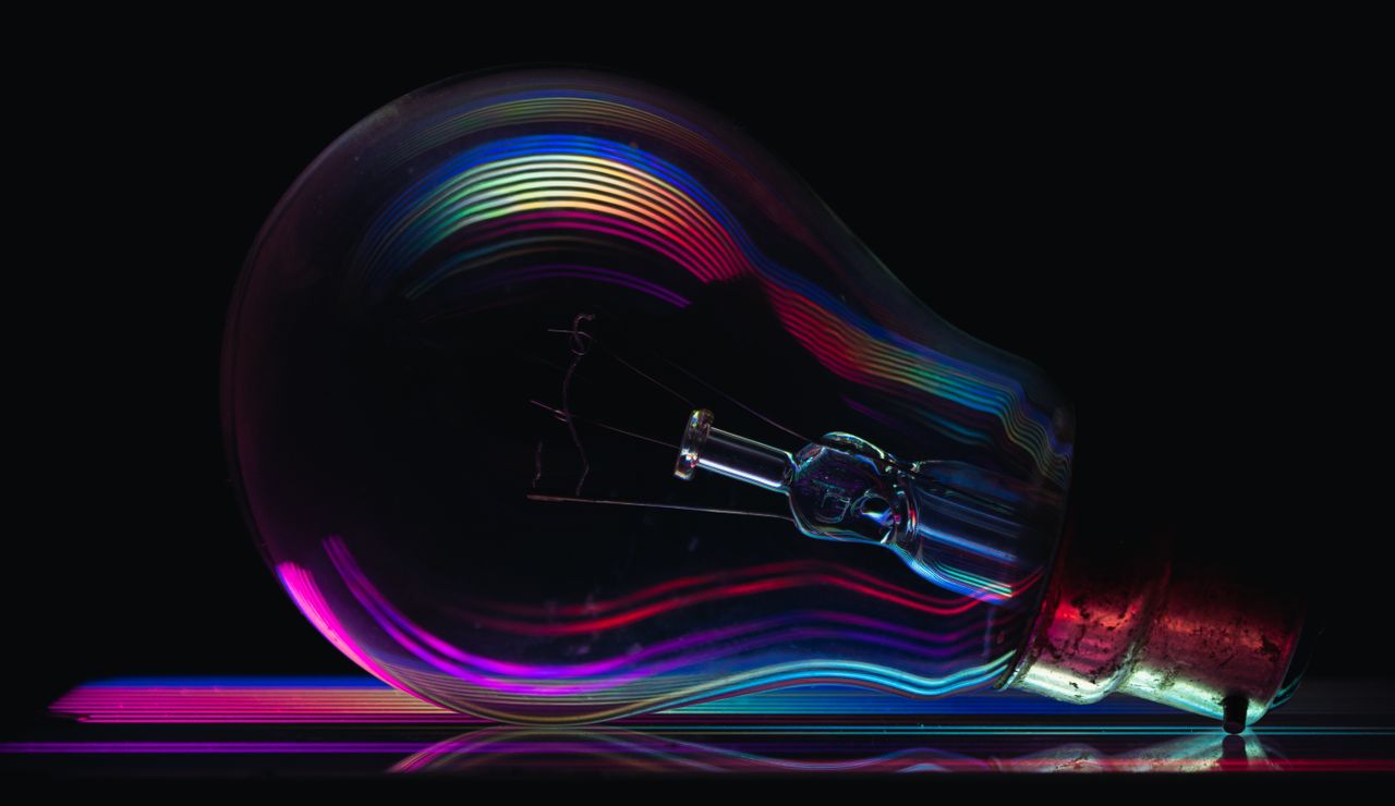 A colorful light bulb showcasing rainbow reflections on a dark background.