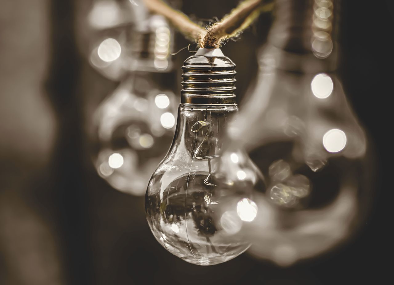 Close-up of vintage light bulbs hanging on a string with a soft, moody background.