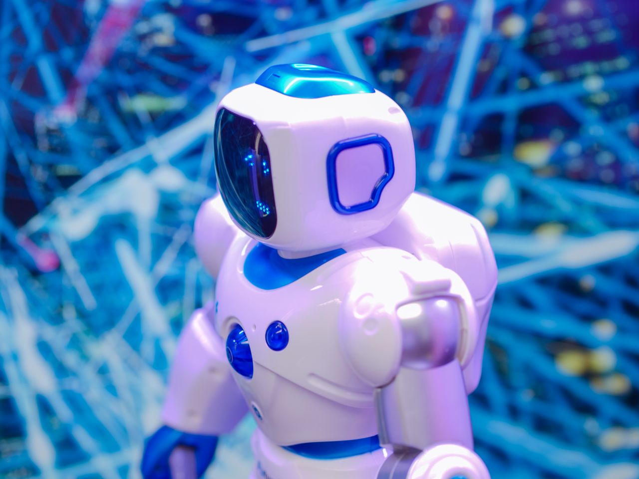 services-05 Close-up of a white and blue robot against a dynamic, futuristic tech backdrop.